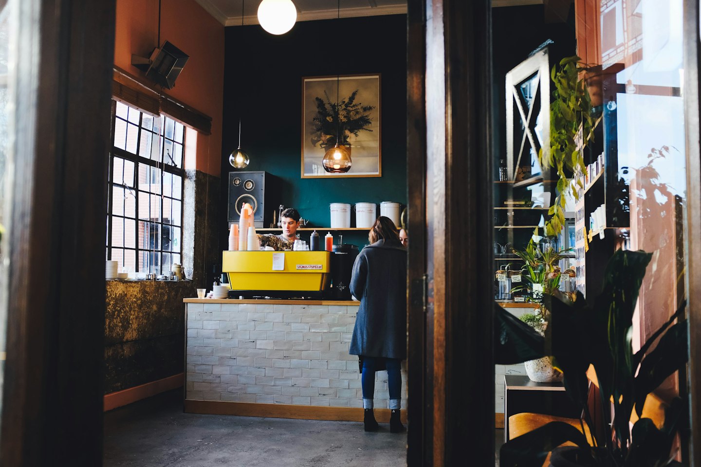 Barista připravuje kávu na žlutém kávovaru v kavárně.